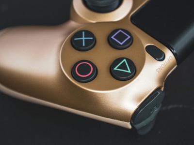 Detailed shot of a gold gaming controller with iconic buttons. Perfect for tech and gaming stock images.